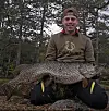 Simon poserar med en stor gädda framför en skog.